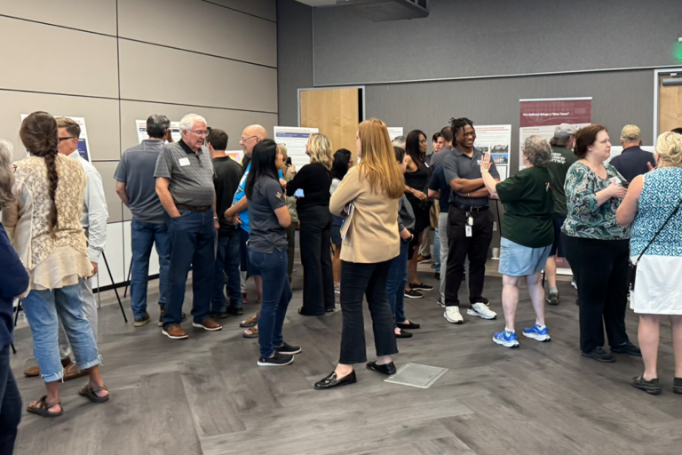 about 24 people standing and discussing display boards about zoning districts