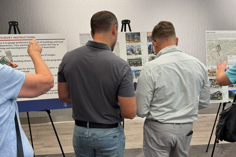 two men viewed from the back discussing a display board about zoning districts